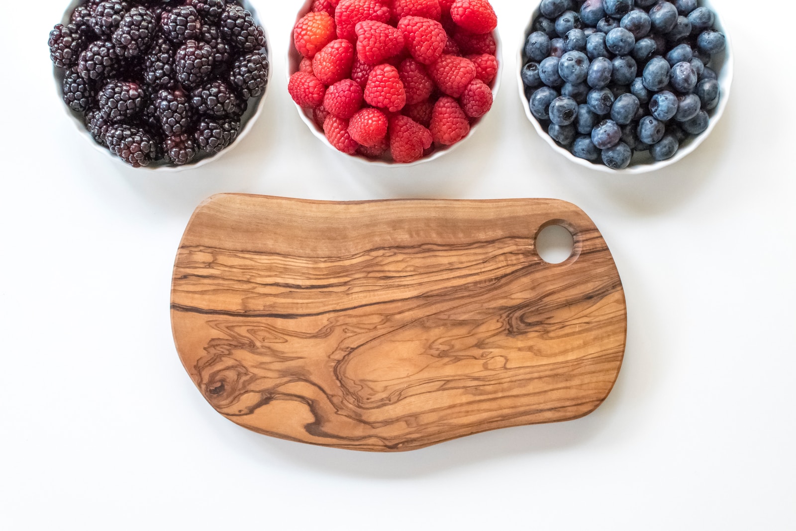 red raspberry and blue berries on brown wooden chopping board